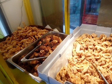 Chicharrones in three metal serving dishes with tongs.