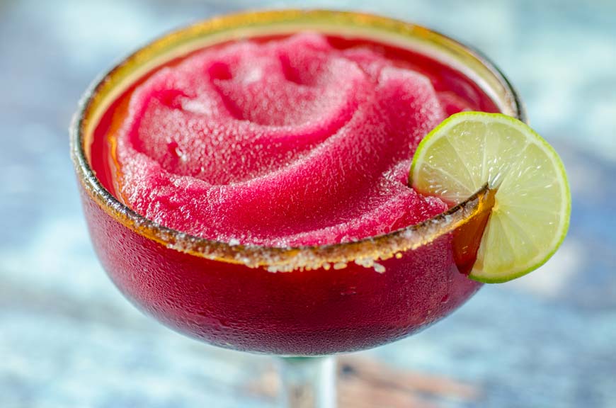 frozen pink margarita in glass with lime and salt