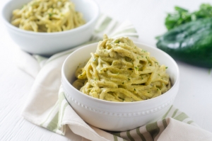 spaghetti on green poblano sauce in a white bowl