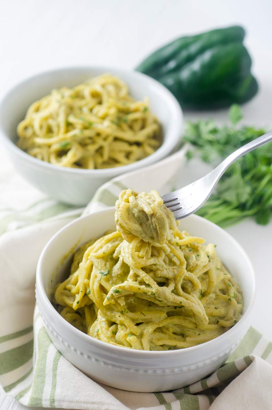 spaghetti on green poblano sauce in a white bowl