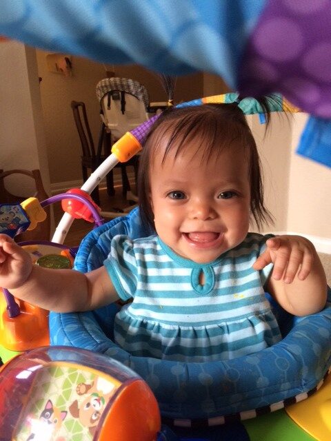 A cute little girl in a blue dress in a walker.