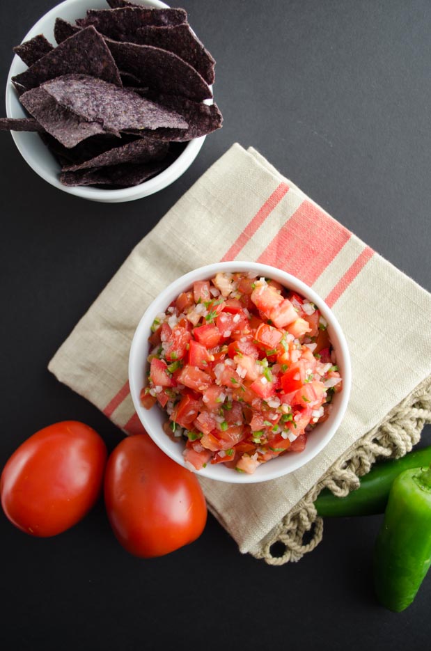 Top view of a small white bowl with fresh pico de gallo set on a kitchen towel.