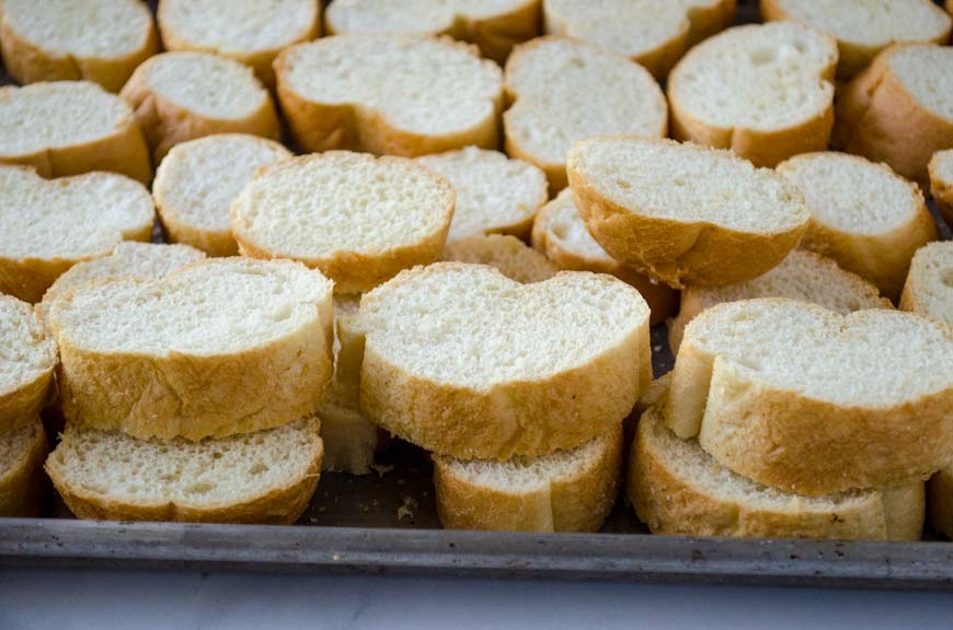 Sliced baguette filling a metal baking sheet.