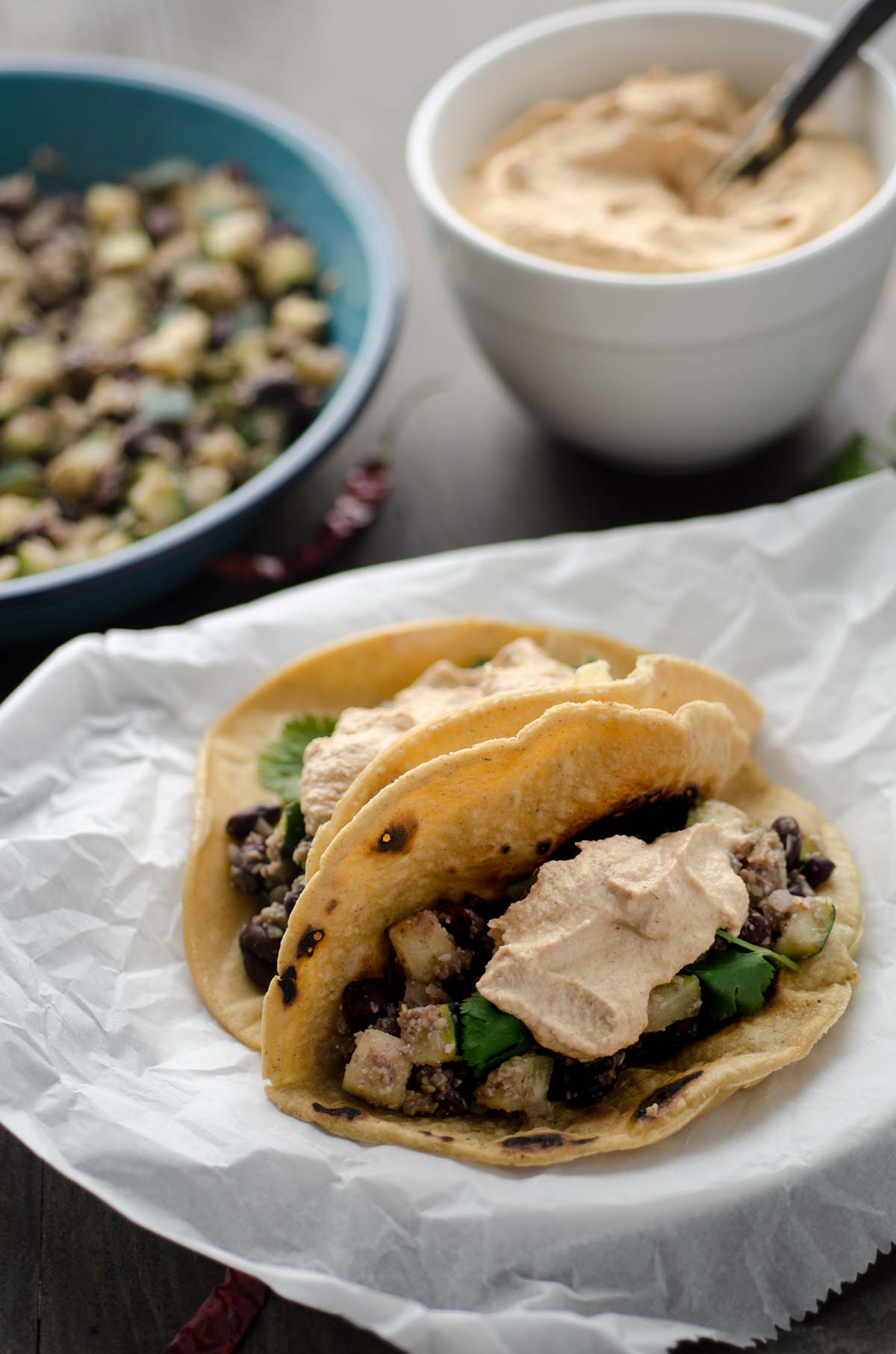 Spicy zucchini and black bean tacos on a parchment lined plate.