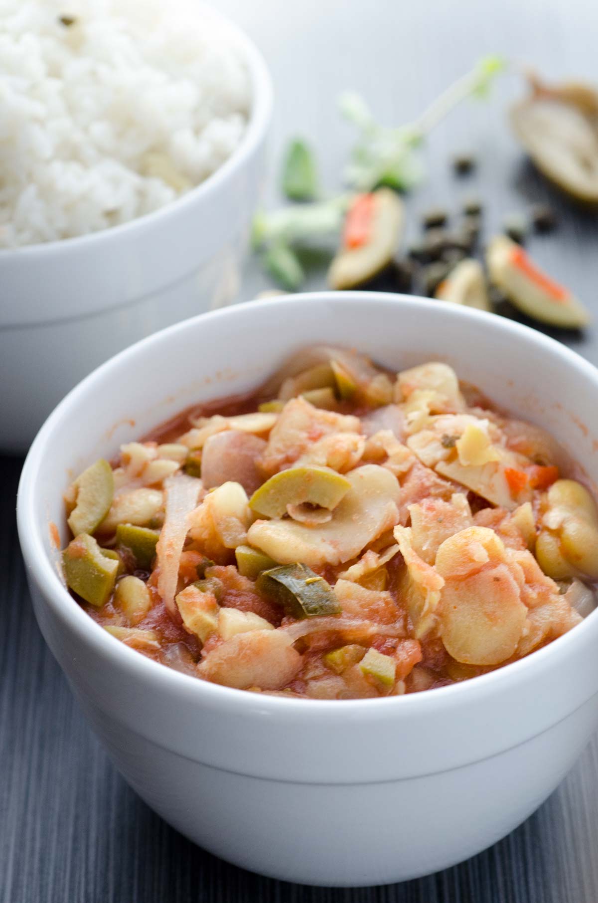 Veracruz-style fava bean stew in a small white bowl with a bowl of white rice in the background.