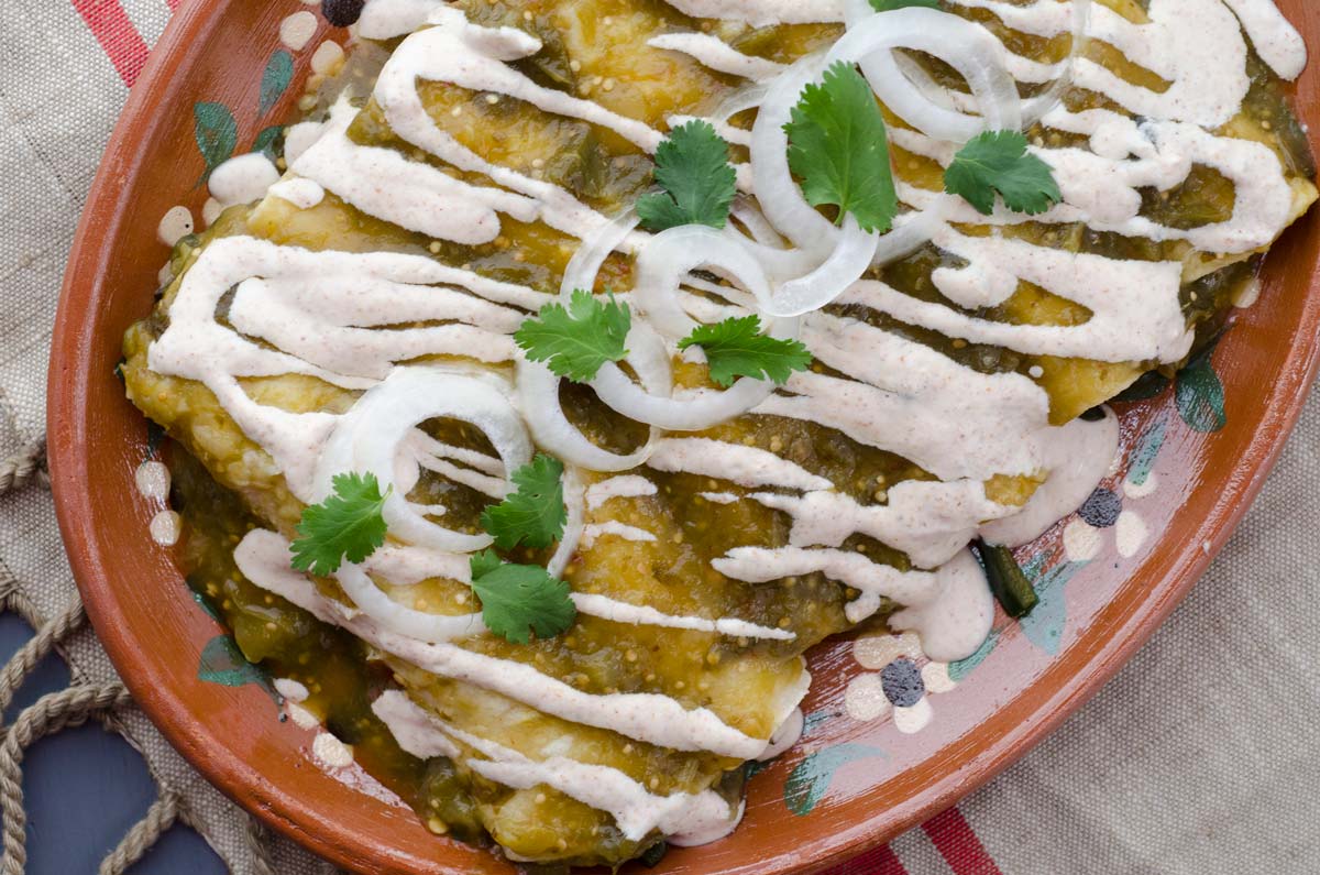 Vegan roasted tomatillo enchiladas, filled with sautéed onions, garlic, poblano peppers, and pinto beans. Bathed in salsa and almond crema.