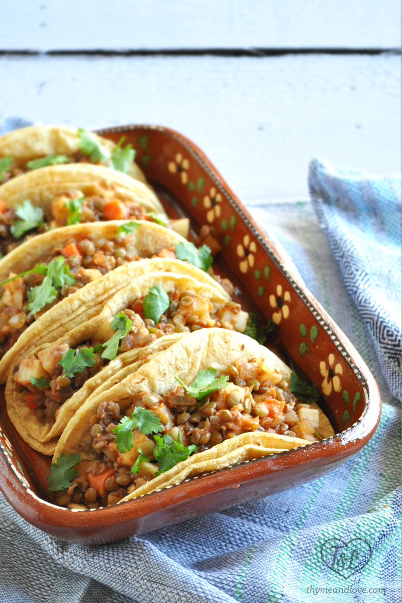 Lentil Picadillo filled corn tortillas in a red baking dish.
