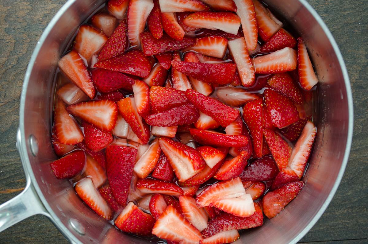 Diced strawberries with water in a saucepan.