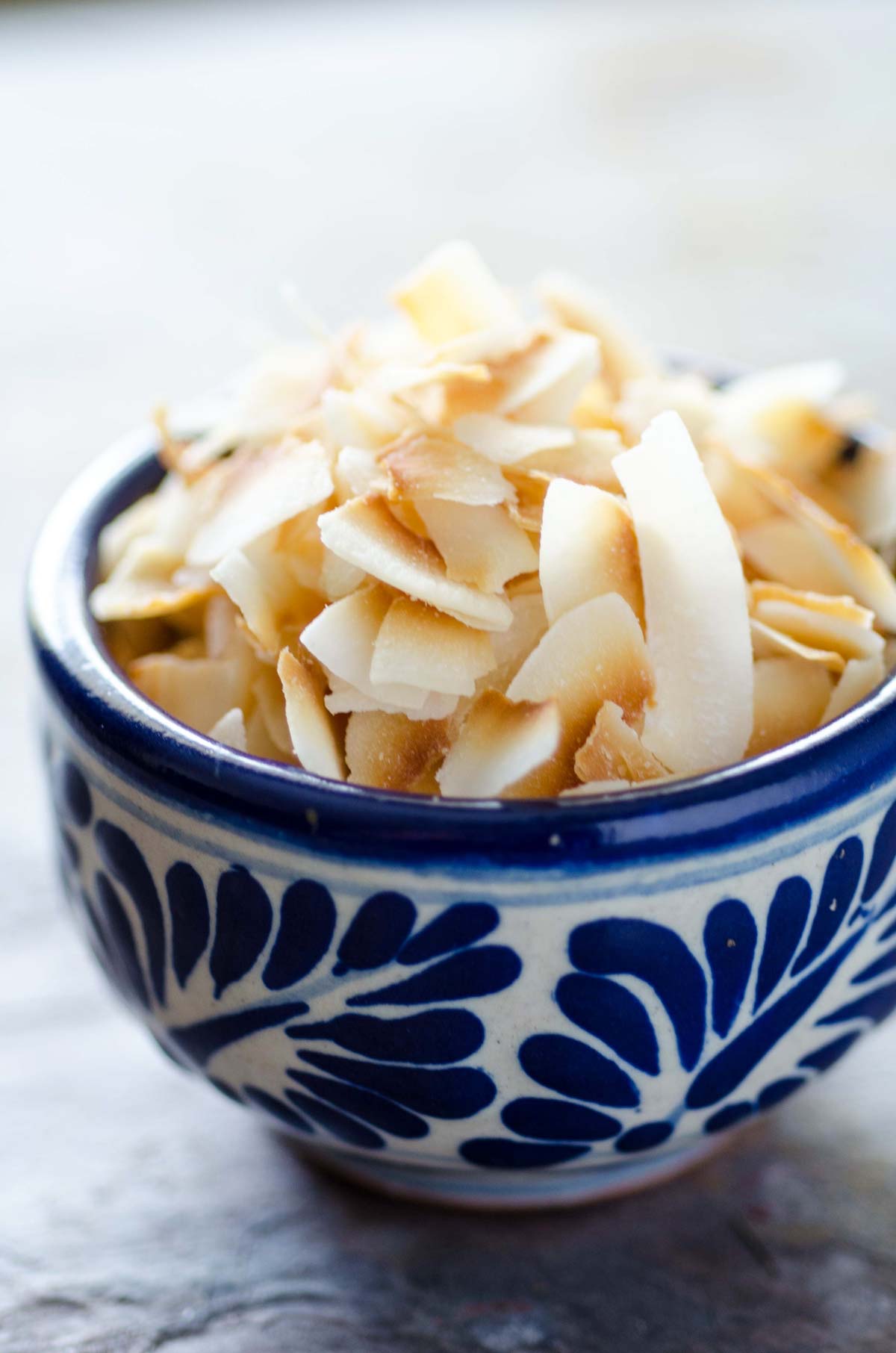 Toasted coconut flakes in a small blue and white patterned bowl.