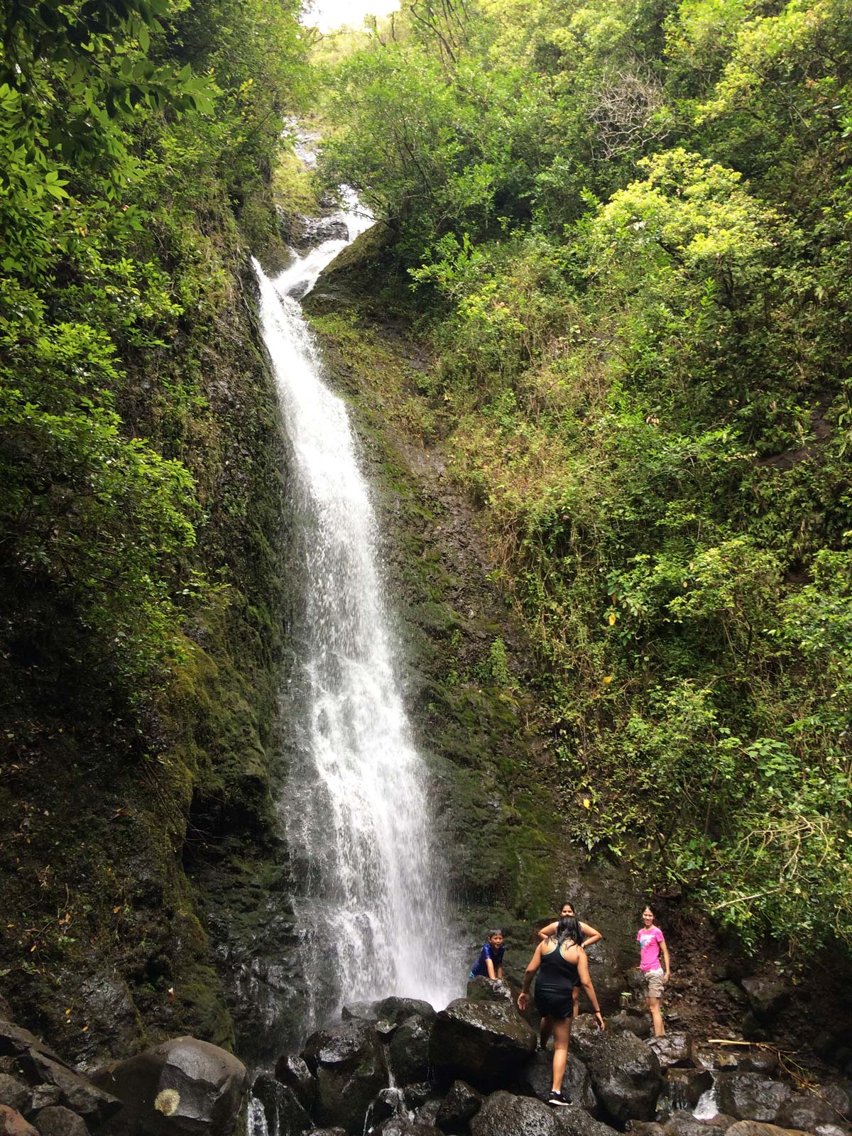 Several people at the bottom of a waterfall.