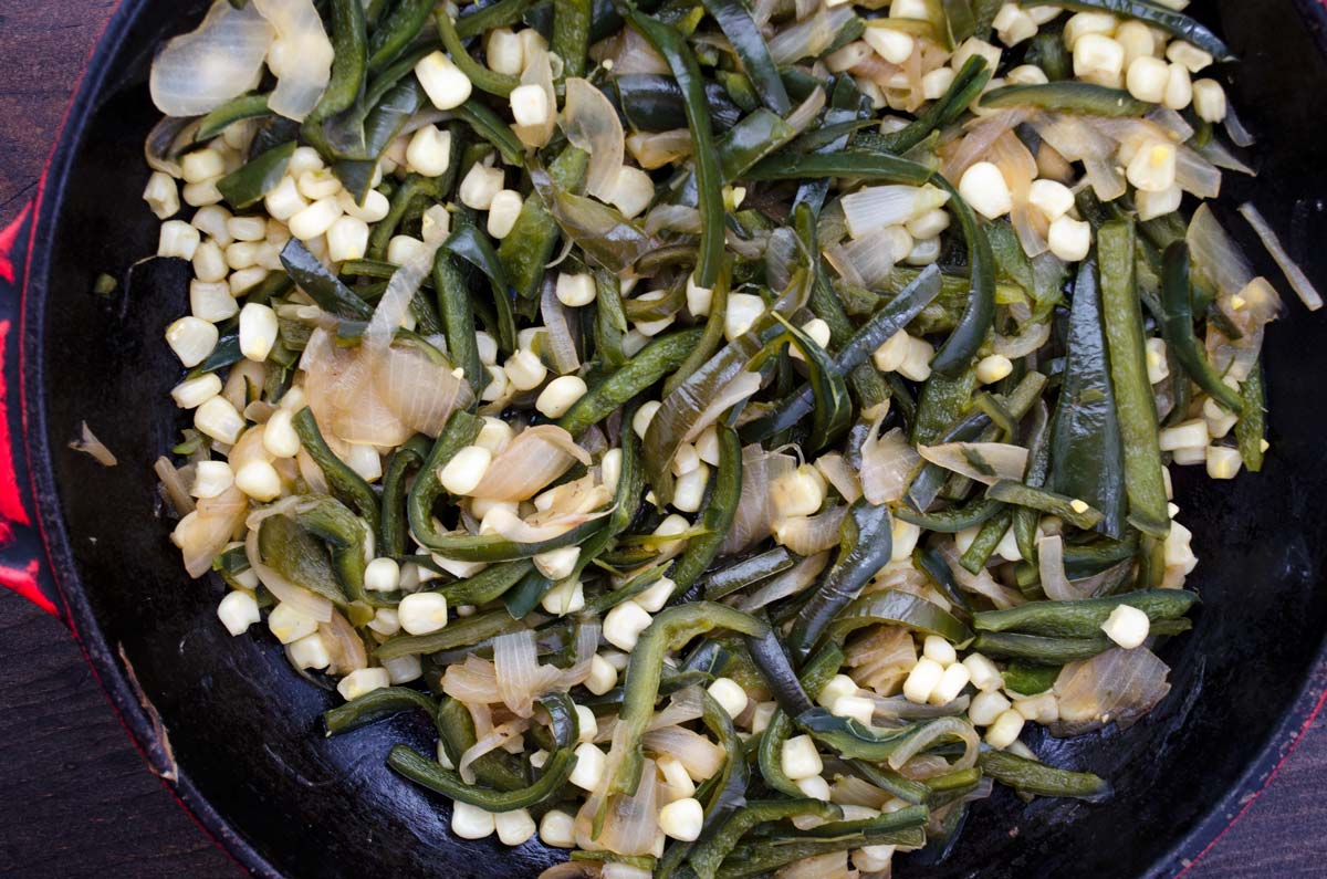 Poblano, onions, and white corn sauteeing in a cast iron skillet.