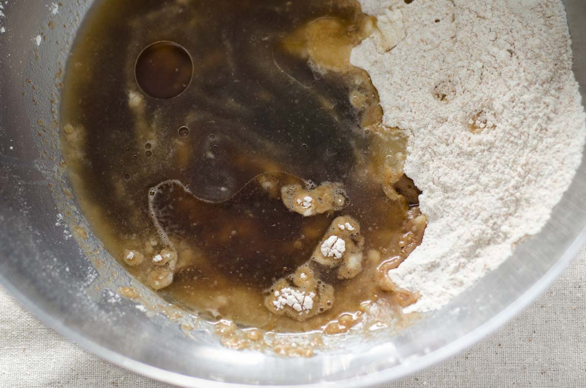 Flour mixed with piloncillo syrup in a stainless steel bowl.