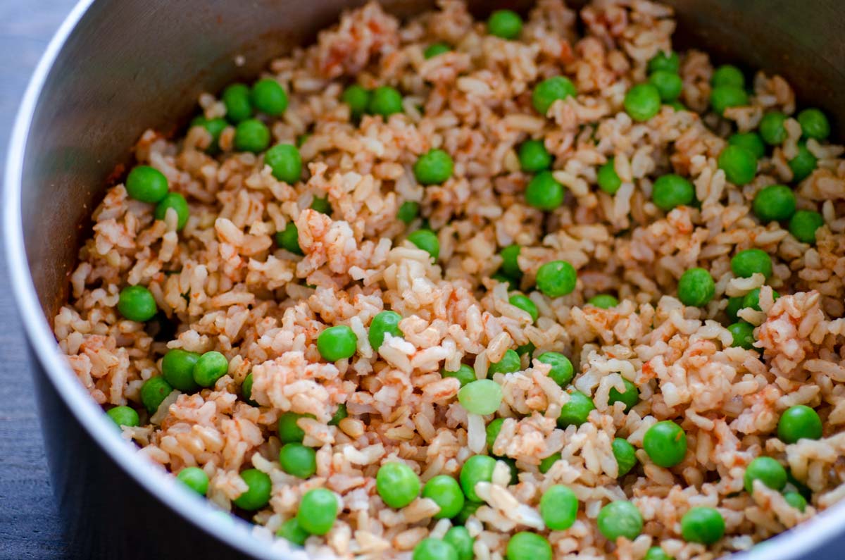 Frozen peas mixed into a saucepan of Mexican brown rice.