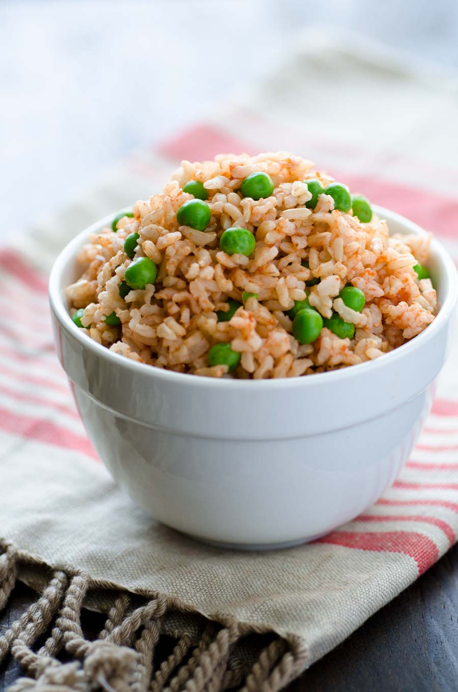 Small white bowl of Mexican brown rice with peas.