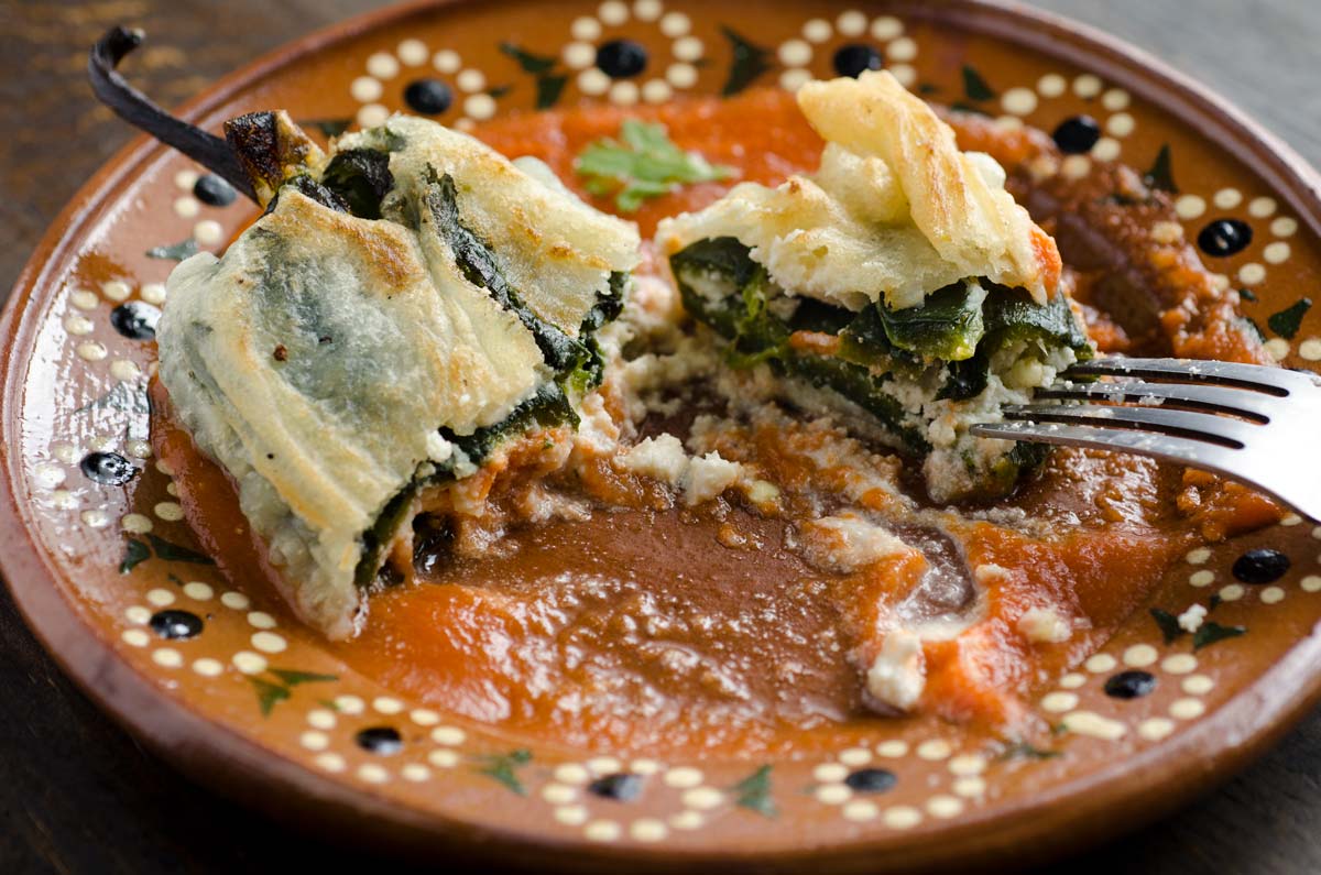 A vegan chile relleno on a brown clay plate.