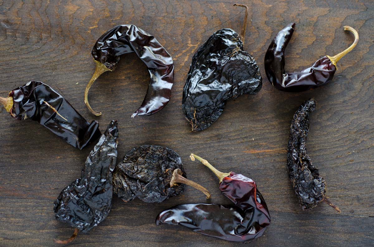 Chile guajillo and chile ancho on a dark wooden surface.