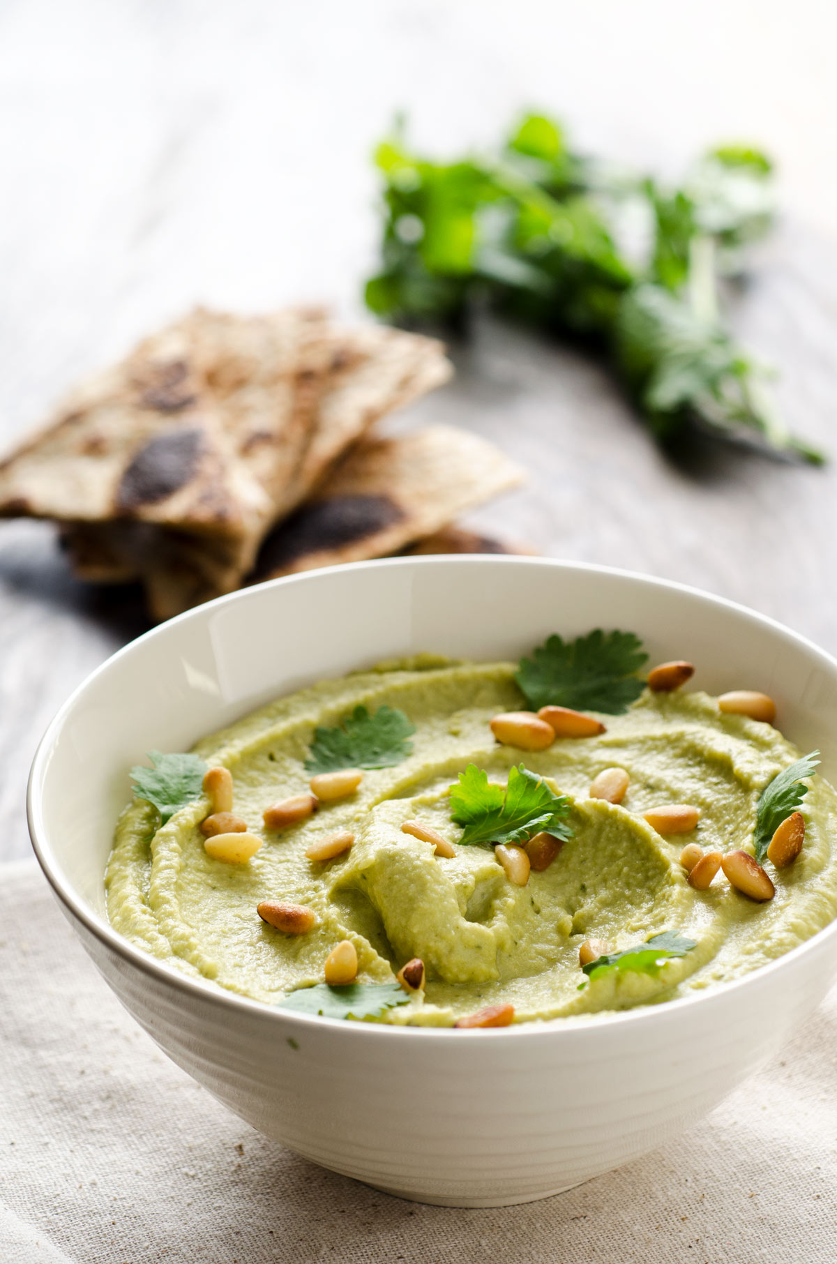 Closeup of a small white bowl of roasted poblano hummus.