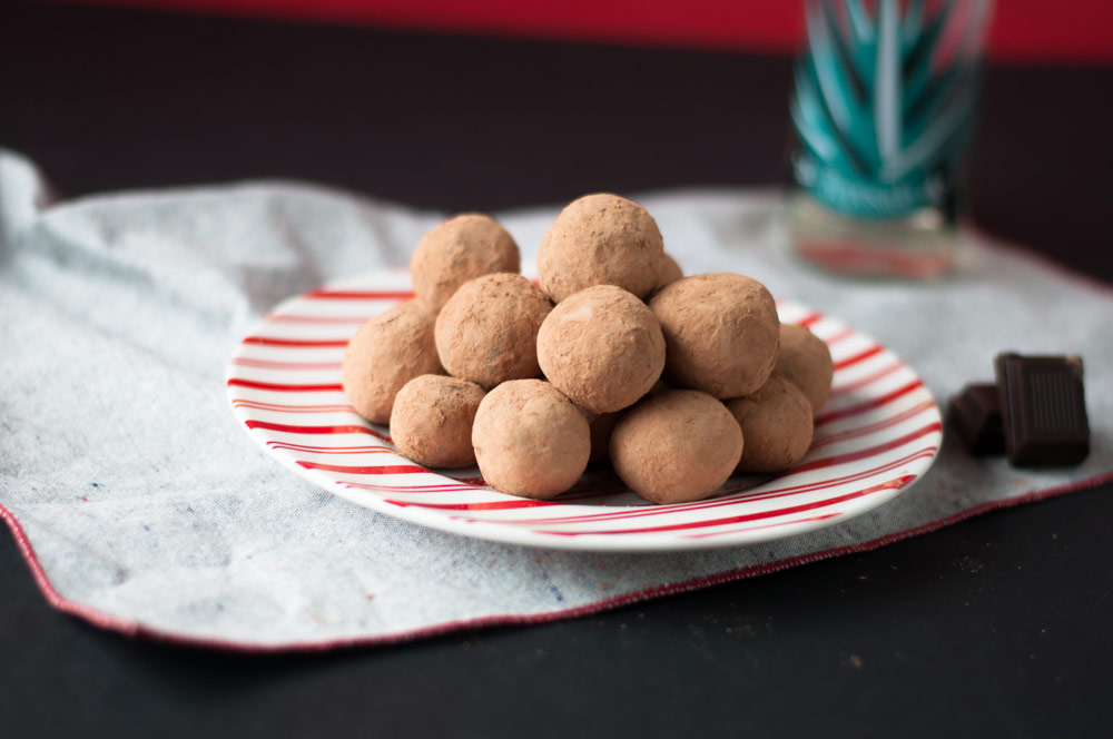 Vegan Tequila Truffles stacked on a white and red striped plate sitting on a white towel.