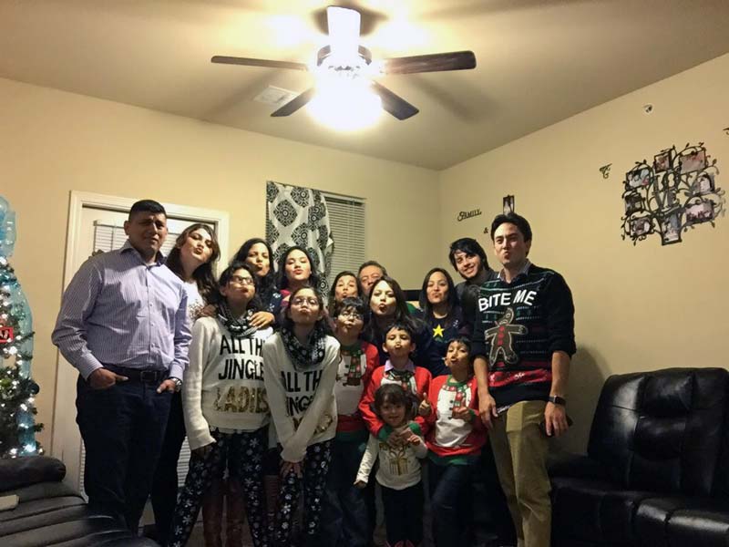 Family photo in a living room ith a Christmas tree.