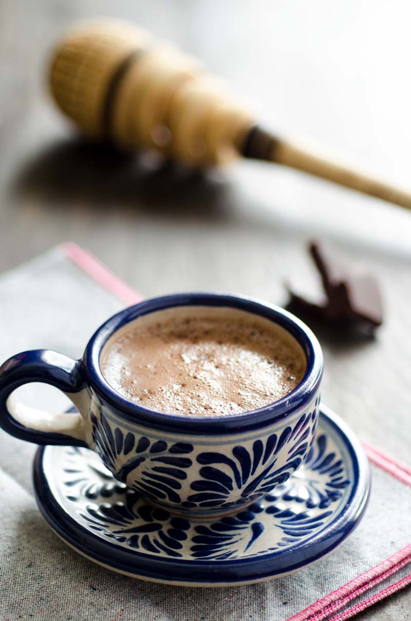 A blue and white patterned mug on a matching saucer filled with Mexican hot chocolate.