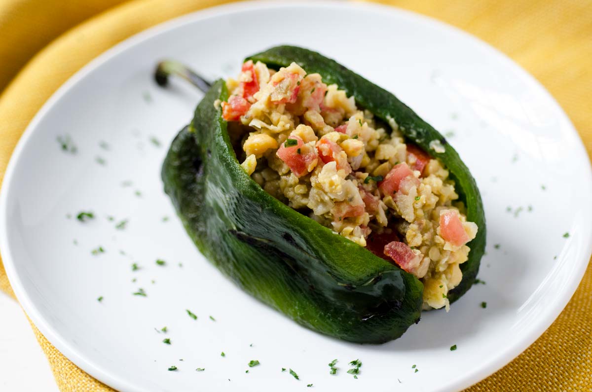This vegan chickpea tuna salad of mashed chickpeas, tomato, onion, serrano pepper, mayo, olives, and capers is stuffed into a poblano pepper.
