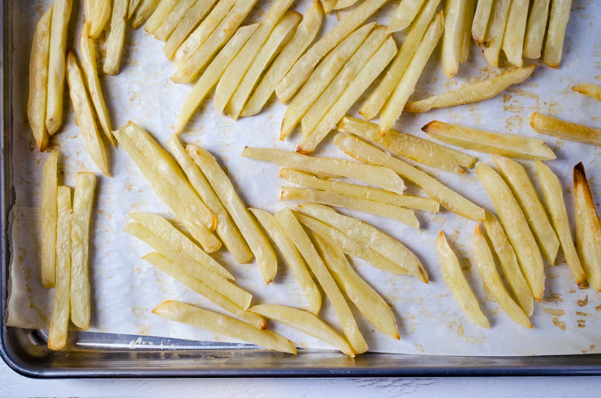 Oven baked fries on a parchment lined baking sheet.