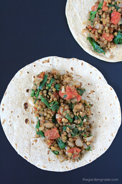 Top view of lentil spinach burrito filling on an open flour tortilla.