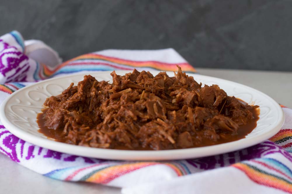 Jackfruit chilorio on a white platter over a colorful kitchen towel.