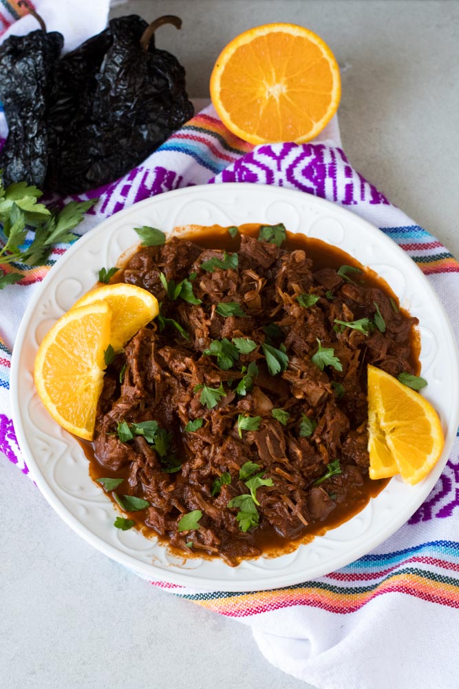 Jackfruit chilorio in a white serving bowl topped with orange slices.