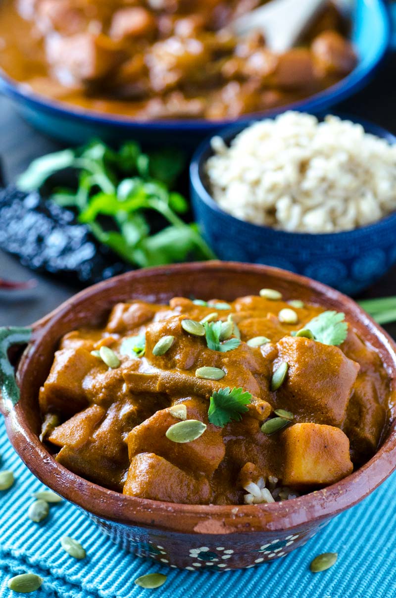 Pipian Rojo Over Rice in a small brown bowl.