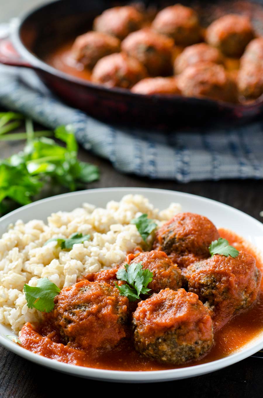 Tofu meatballs and red sauce next to rice on a white dinner plate.