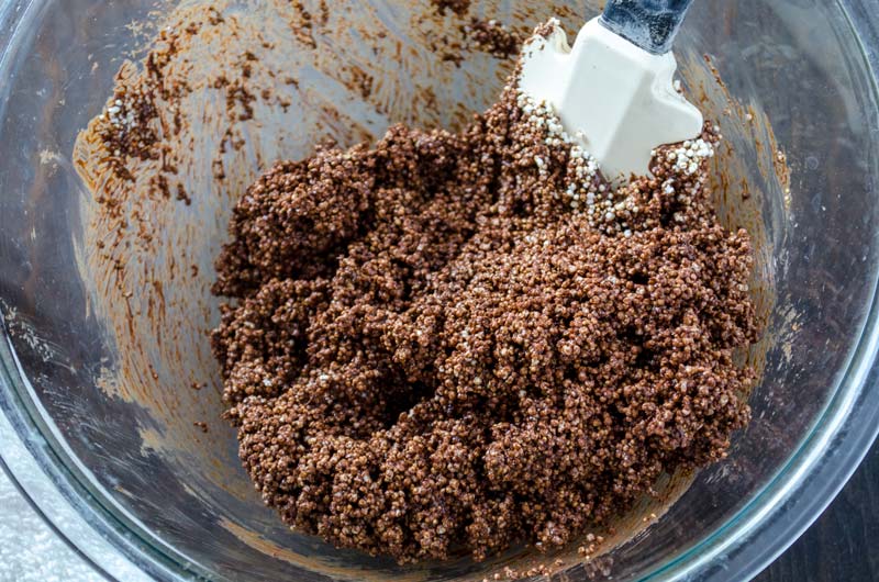 Chocolate and amaranth with a rubber spatula in a glass mixing bowl.