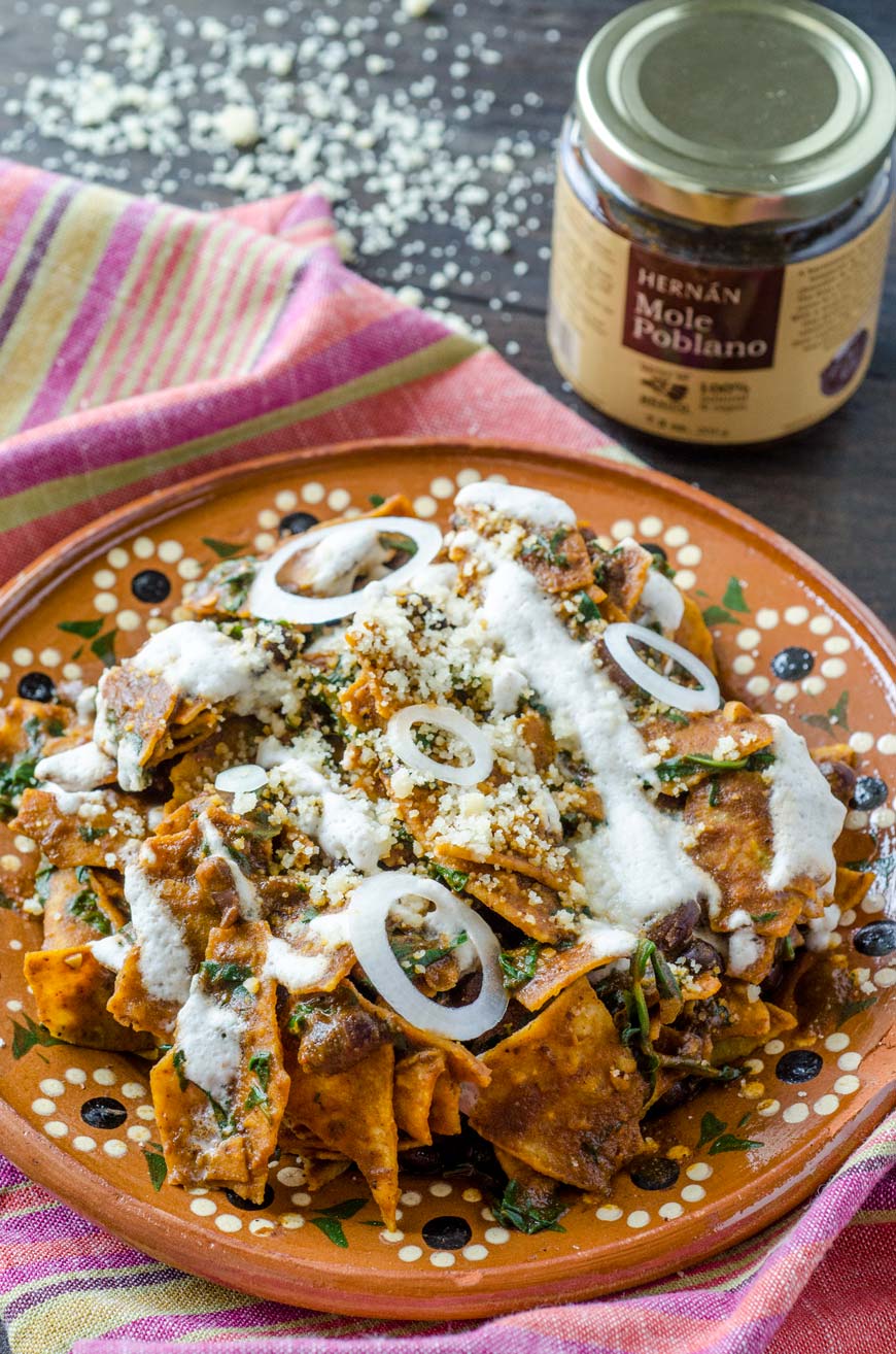 Vegan mole chilaquiles are tortilla chips covered in mole sauce and mixed with sautéed greens and black beans, then drizzled with an almond crema, and vegan queso cotija. The combination is seriously good.