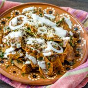 Vegan mole chilaquiles are tortilla chips covered in mole sauce and mixed with sautéed greens and black beans, then drizzled with an almond crema, and vegan queso cotija. The combination is seriously good.