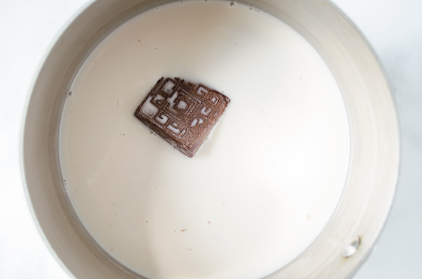 A square of Mexican chocolate in a saucepan of warm milk.