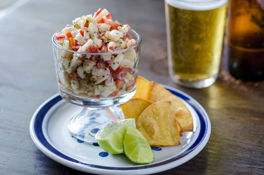 Hearts of palm ceviche on a blue plate with chips, and a beer.