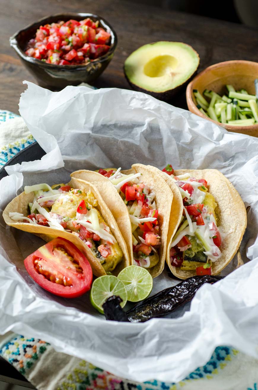 Vegan fish tacos in a cast iron pan with limes, tomato, and avocado