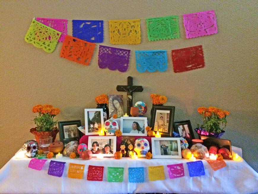 Altar de muertos, a table with pictures, candles, bread, a cross