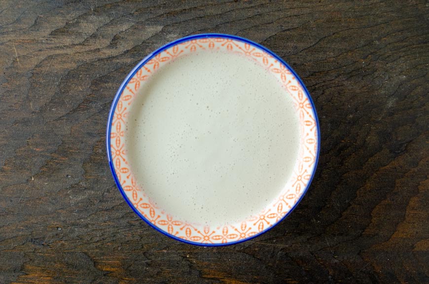 Bowl of sweet cream on a dark wooden surface.