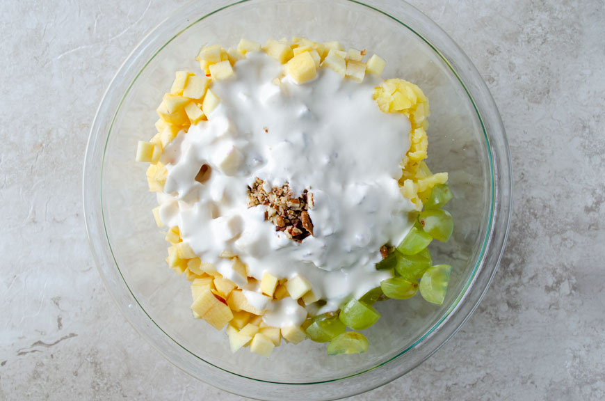 Sweet cream poured over fruit in a glass bowl.