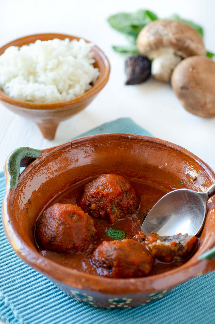 4 vegan meatballs in a clay bowl on a blue kitchen towel.