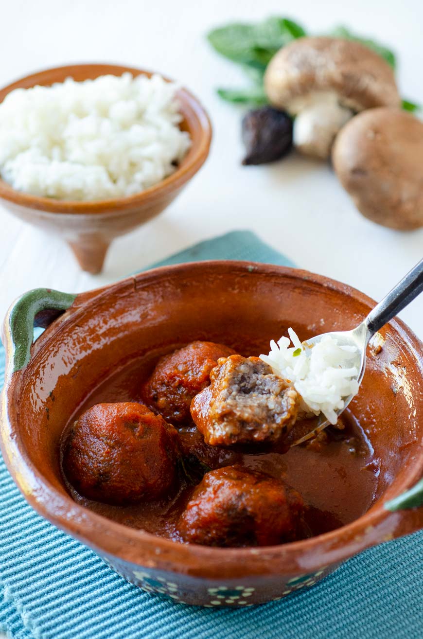 4 vegan meatballs in a clay bowl on a blue kitchen towel .