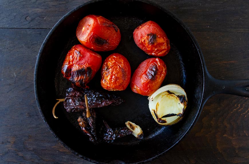 Roasted tomatoes, onion, dried peppers, and garlic in a cast iron pan.