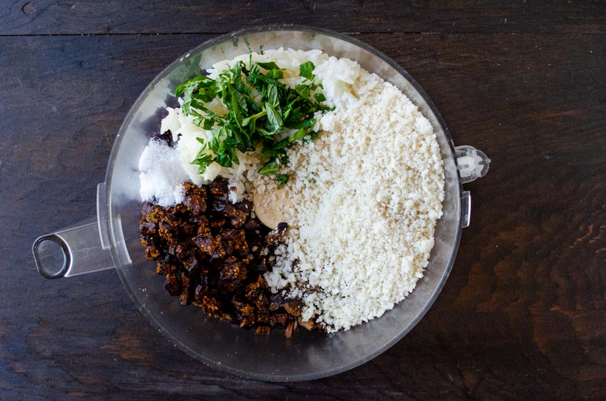 Bread crumbs, mushrooms, rice, and beans in the bowl of a food processor.