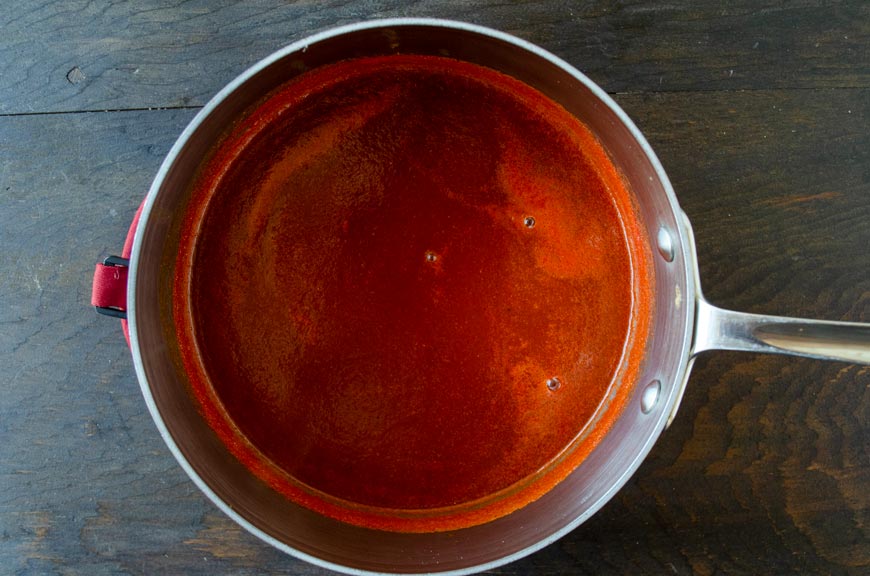 Tomato chile broth in a stain less steel sauce pot.