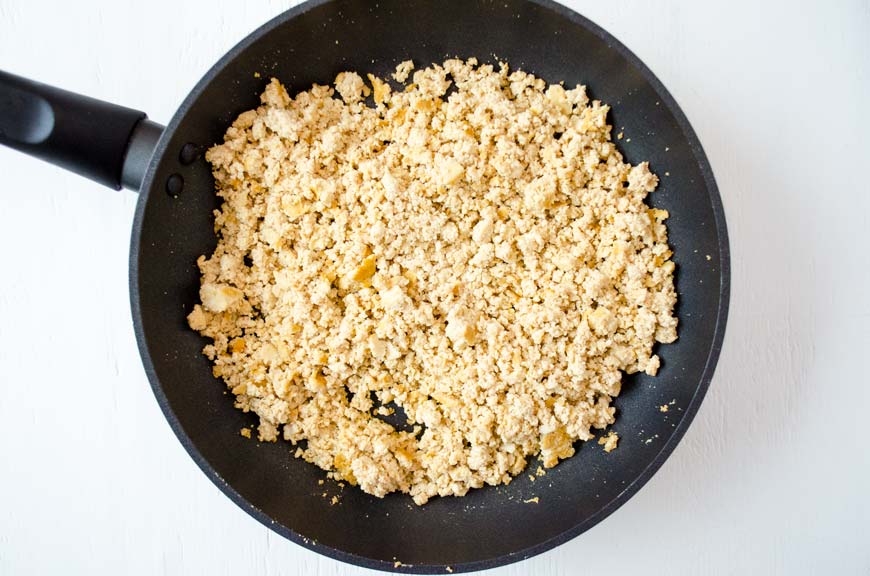 Tofu cooking in a black non-stick saute pan 