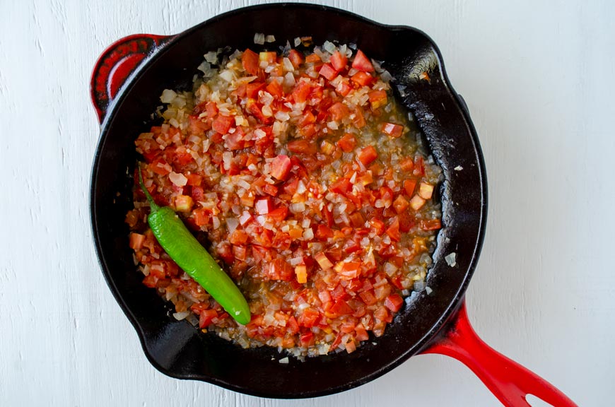 Saute pan with a cooked mixture of tomato, onion, garlic and chile serrano.