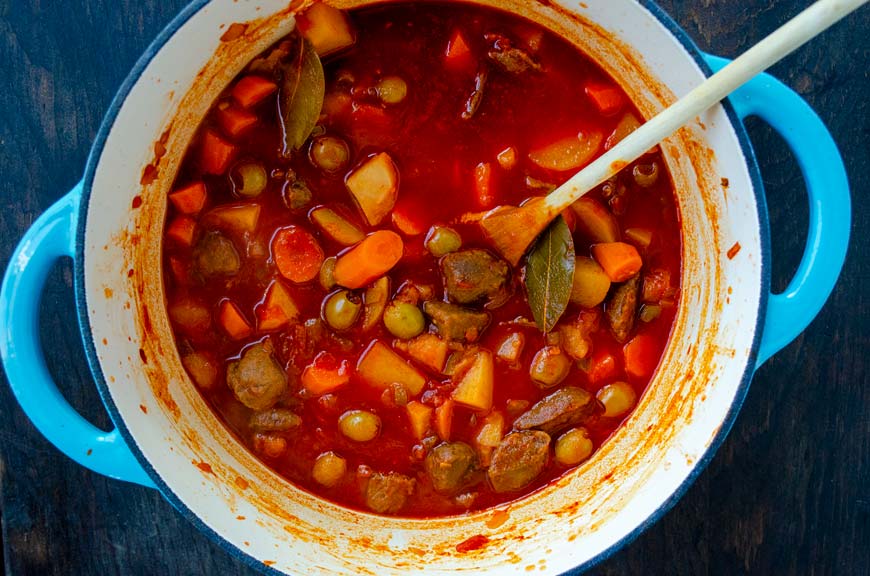 Vegan barbacoa sinaloense in a blue and white pot with a wooden spoon in it.