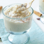 Vegan arroz con leche in a glass goblet with a golden spoon inserted into the cup.