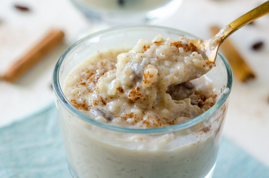 A close up of vegan arroz con leche with raisins with the spoon digging in.